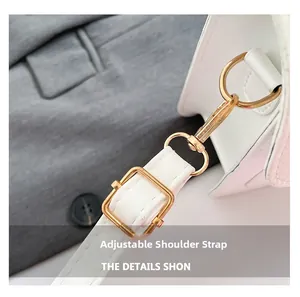 Detail of adjustable shoulder strap with golden lobster clasp on white leather bag