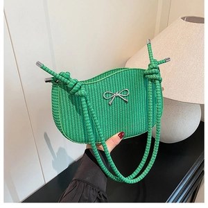 Close-up of green woven handbag featuring a silver metal bow and textured rope handle