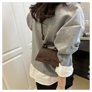 Deep brown pebble leather crossbody bag styled on a model in a bright minimalist interior