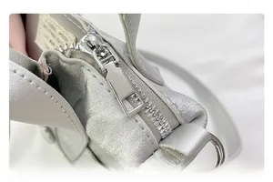 Detailed close-up of silver leather texture and premium metal zipper on a square bag