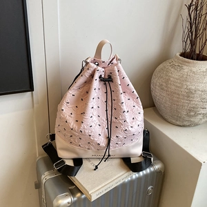Pink drawstring backpack with black bow patterns on a silver suitcase for travel style