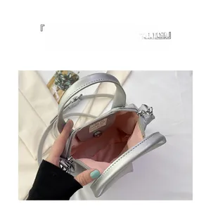 Detail view of silver mini handbag showing pink fabric lining and interior storage space