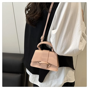 Side view of pink textured leather crossbody bag with curved base on fashion model