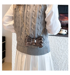 Dettaglio della mini borsa metallizzata a fiocco marrone con catena dorata sottile