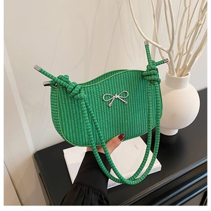 Detailed macro view of the vivid green woven shoulder bag with silver metal bow accent
