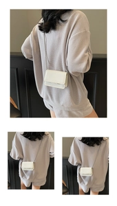 Detail view of white mini patent leather crossbody bag with delicate stone pattern and chain