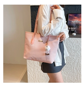 Detail of pink woven tote bag with gold metal plate and fluffy white eye charm