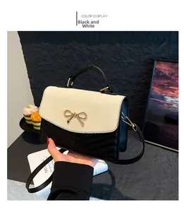 Detail of minimalist black and white crossbody bag with golden butterfly buckle and V-texture