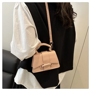 Model wearing light pink pebbled leather mini crossbody bag with top handle and flap