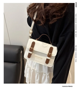 White leather crossbody bag styled with black sweater and white pleated skirt
