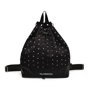 Black drawstring backpack featuring white bow prints and premium leather bottom detail
