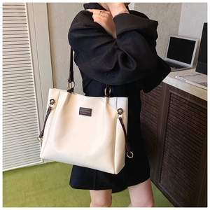 Detail of minimalist beige and brown leather tote bag with elegant gold brand plaque