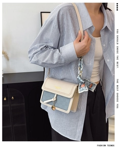 Detail of color-block crossbody bag with silk scarf and gold lettering on the flap