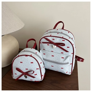 Detailed comparison of two bow-patterned backpacks with red heart pendants in a set