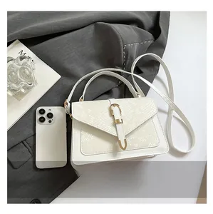 Detailed view of white embossed leather handbag with gold buckle and phone for scale