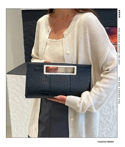 Detail of black crocodile texture clutch bag with silver rectangular metal handle