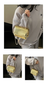 Detailed view of crocodile-embossed patent leather texture and silver chain strap on mini bag