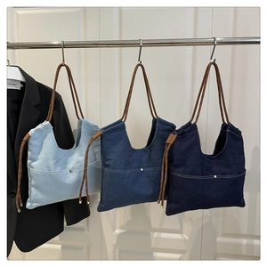 Close-up of denim canvas tote bags in three blue shades with rope handles and pockets