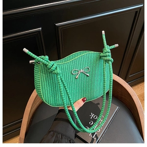 Detail of bright green woven shoulder bag featuring a silver metal bow and rope strap