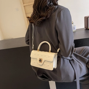 Beige quilted leather handbag with clover clasp shown in a stylish over-the-shoulder shot