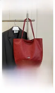Detail of red woven texture tote bag featuring a leather Fashion tag and shoulder straps
