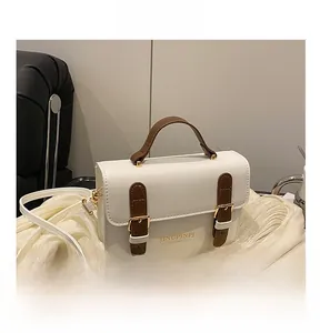 Detail of white leather shoulder bag with brown straps, gold buckles and gold lettering