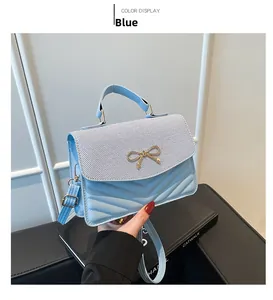 Detail of light blue crossbody bag with gold butterfly accent and V-quilt pattern