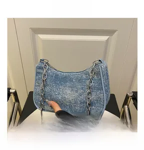 Close-up of light blue denim underarm bag with silver chain and glitter texture