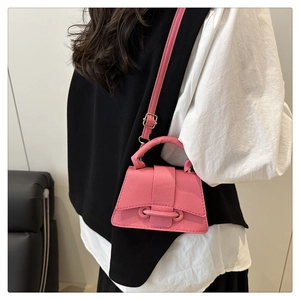Close-up of pink litchi grain leather mini crossbody bag with golden hardware details