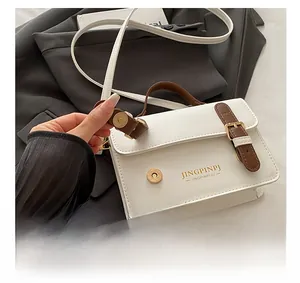 Detail of premium white leather handbag featuring gold magnetic buckle and refined stitching