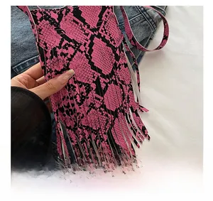 Detail of pink snakeskin print crossbody bag with long fringe tassels and leather texture