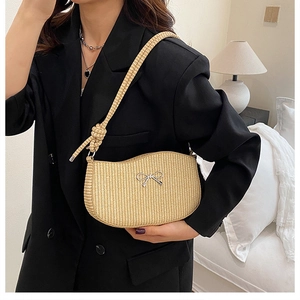 Close-up of beige woven shoulder bag with metal bow detail and knotted rope handle