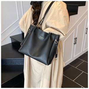 Detail of minimalist black leather tote bag with elegant gold hardware and refined texture