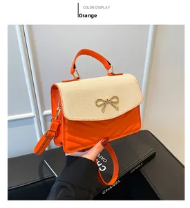 Detail of orange lychee PU leather and straw flap with golden bow clasp crossbody bag