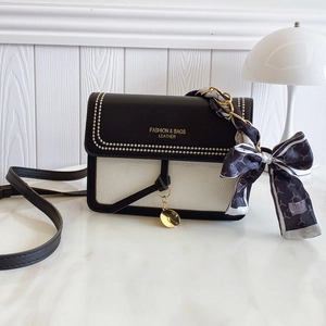 Elegant black and white leather crossbody bag with gold dots and silk scarf chain handle