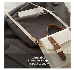 Detail of adjustable leather strap with gold buckle on white and brown crossbody bag