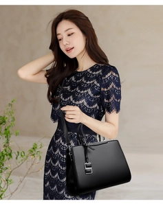 Dettaglio dell'elegante borsa in pelle nera con ciondolo in metallo lucido e trama fine