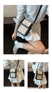 Vertical two-tone woven crossbody bag detail showing gold floral clasp and cute charm