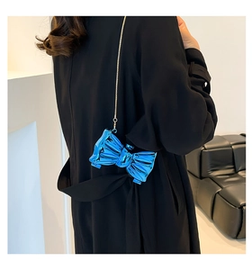 Modella che indossa una pochette a fiocco blu metallizzato con catena d'oro