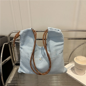 Light blue denim tote bag with woven handles on a chair, minimalist summer fashion style
