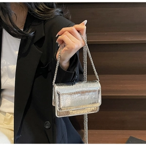 Detail of silver crocodile pattern mini bag with metallic chain and glossy finish