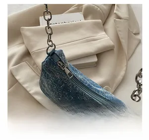Detail view of denim shoulder bag with silver chain strap and smooth metal zipper