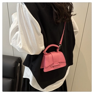 Detail of pink mini leather crossbody bag with curved base and litchi grain texture