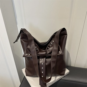 Dark brown faux leather tote bag with large bow and silver rhinestones on a minimalist background