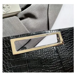 Close-up of black crocodile embossed leather handbag with silver rectangular metal handle