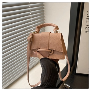Close-up of litchi grain texture on small pink crossbody bag with metal buckle detail