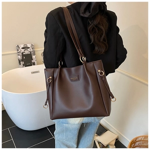 Detail of dark brown faux leather tote bag with gold hardware and shoulder straps