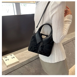 Detailed view of black shirt-shaped handbag with lapel design and decorative buttons