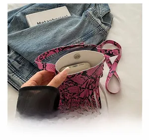 Pink snakeskin pattern mini crossbody bag with fringes showing internal phone storage capacity