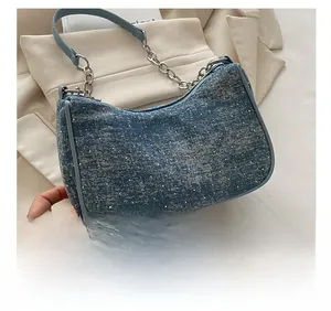 Detail of blue denim shoulder bag featuring sparkling rhinestones and silver chain strap